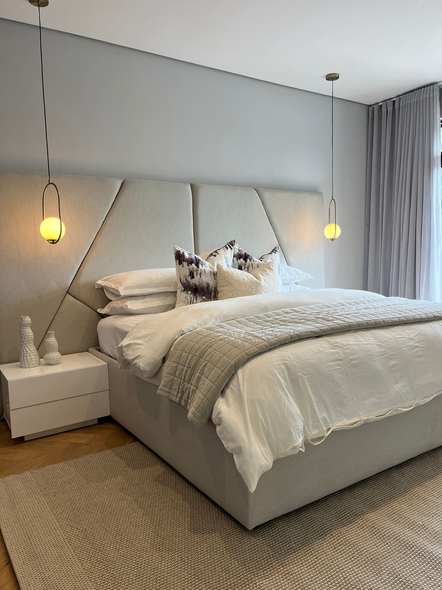 Principal bedroom with upholstered headboard and pendant bedside lighting
