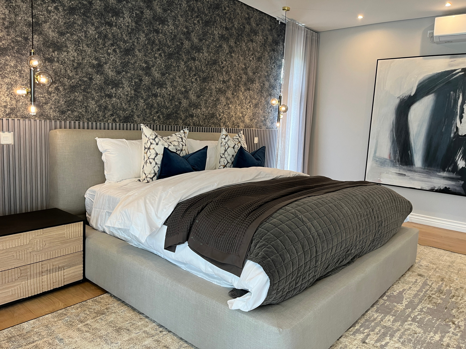 Bedroom with textured feature wall, fluted base and abstract artwork